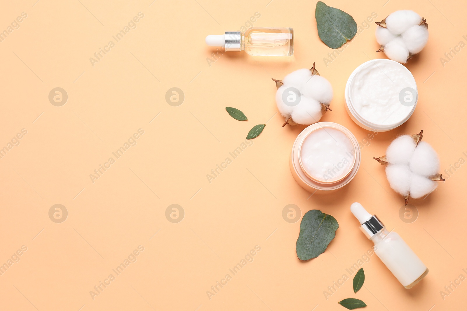 Photo of Different cosmetic products, leaves and cotton flowers on pale orange background, flat lay. Space for text