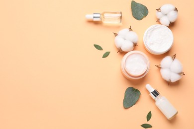 Photo of Different cosmetic products, leaves and cotton flowers on pale orange background, flat lay. Space for text