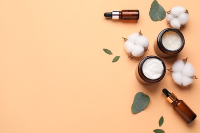 Photo of Different cosmetic products, leaves and cotton flowers on pale orange background, flat lay. Space for text