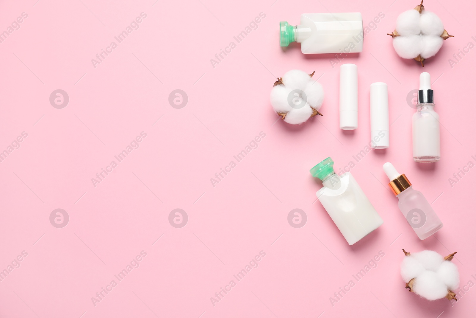 Photo of Different cosmetic products and cotton flowers on pink background, flat lay. Space for text