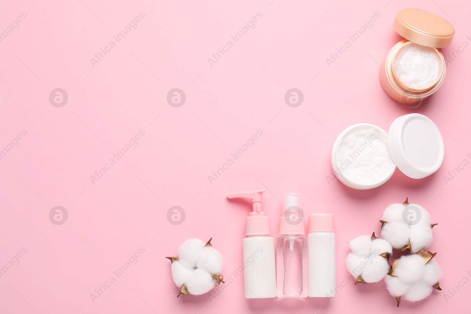 Photo of Different cosmetic products and cotton flowers on pink background, flat lay. Space for text