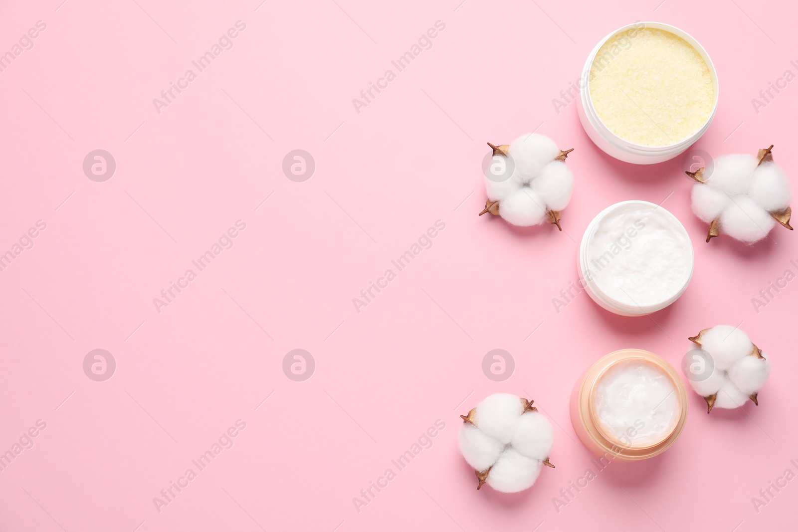 Photo of Different cosmetic products and cotton flowers on pink background, flat lay. Space for text