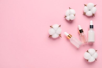 Photo of Different cosmetic products and cotton flowers on pink background, flat lay. Space for text