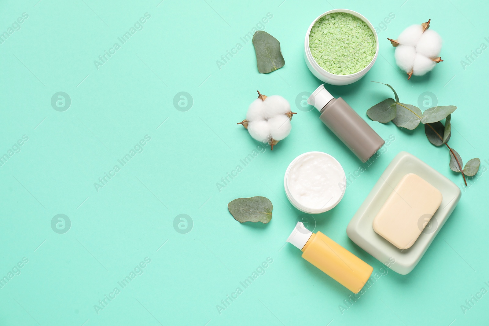 Photo of Different cosmetic products, leaves and cotton flowers on turquoise background, flat lay. Space for text