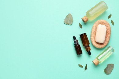 Photo of Different cosmetic products and leaves on turquoise background, flat lay. Space for text