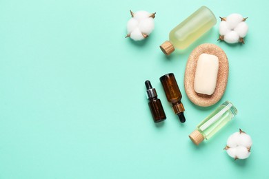 Photo of Different cosmetic products and cotton flowers on turquoise background, flat lay. Space for text