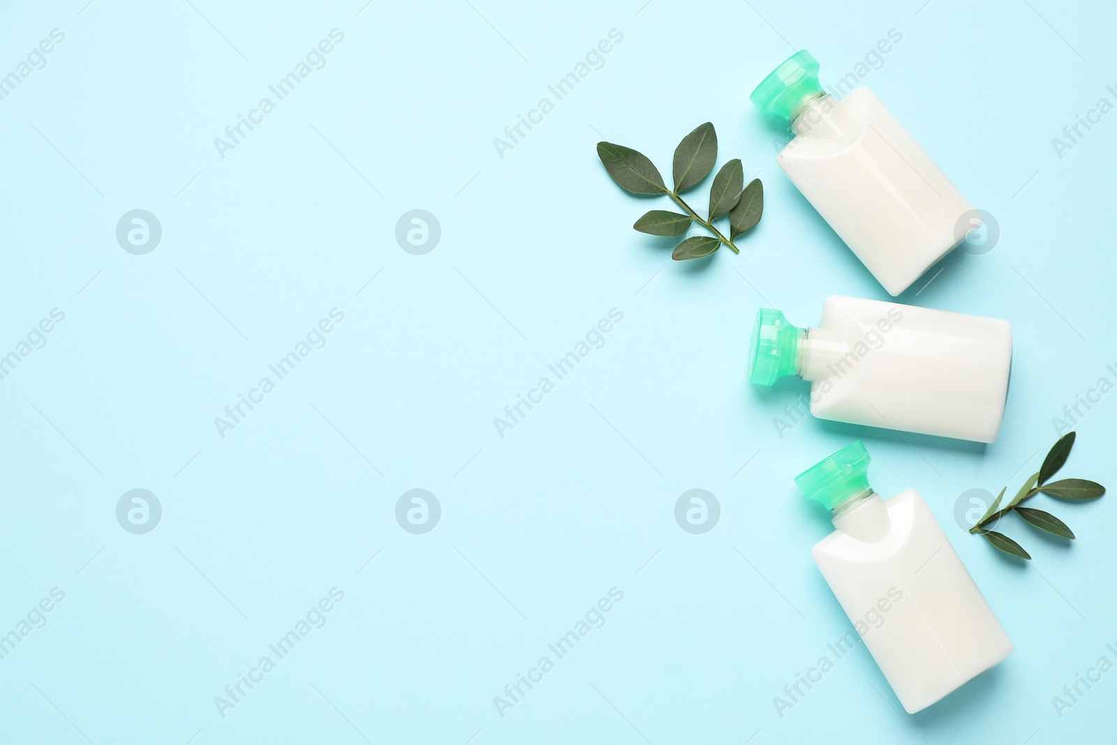 Photo of Cosmetic products and leaves on light blue background, flat lay. Space for text