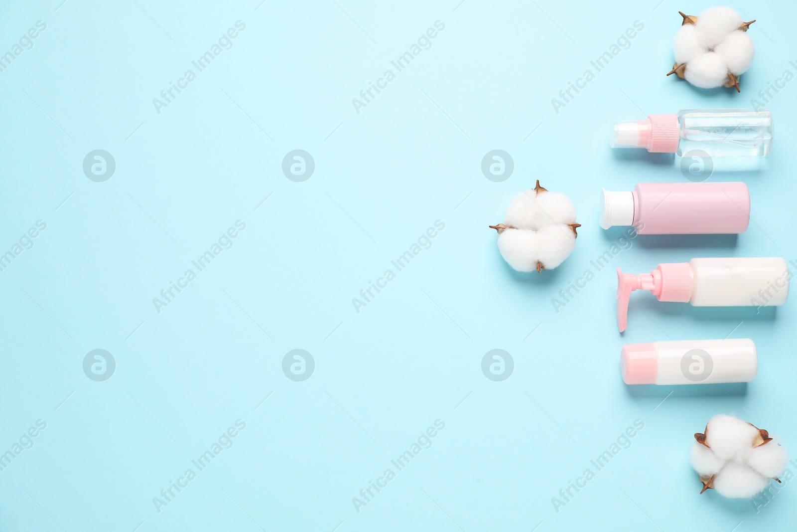 Photo of Different cosmetic products and cotton flowers on light blue background, flat lay. Space for text