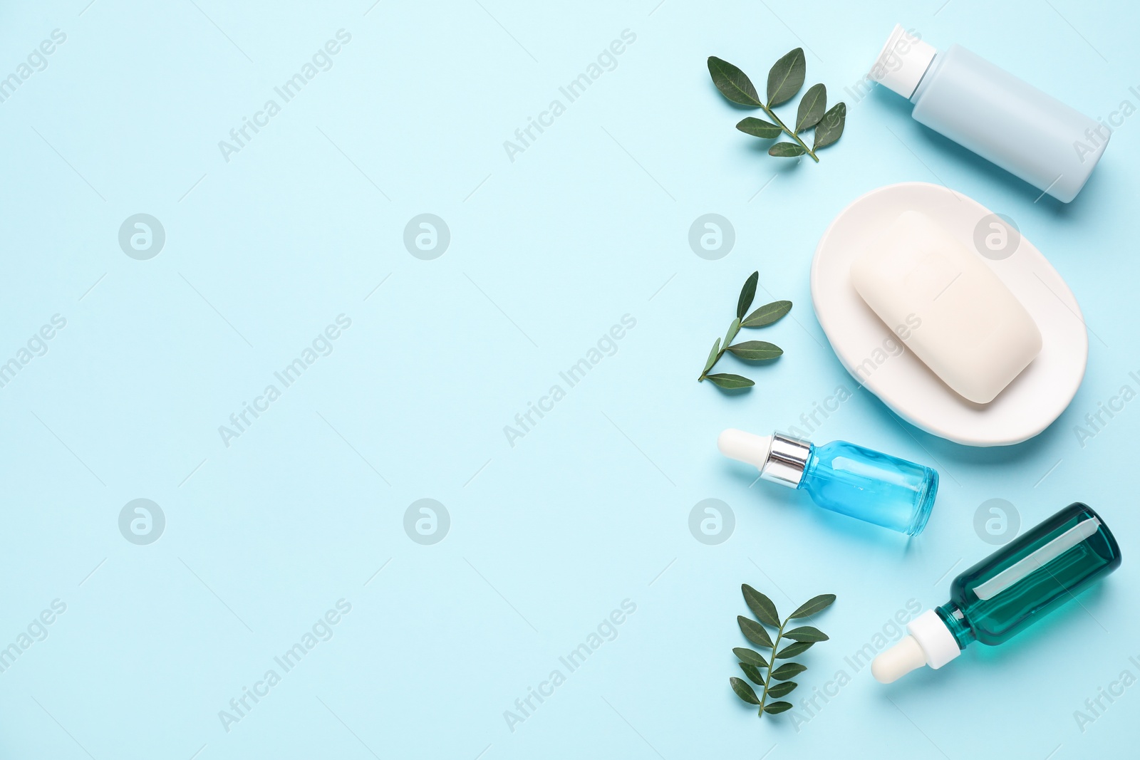 Photo of Different cosmetic products and leaves on light blue background, flat lay. Space for text