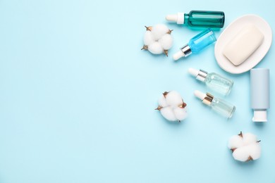 Photo of Different cosmetic products and cotton flowers on light blue background, flat lay. Space for text