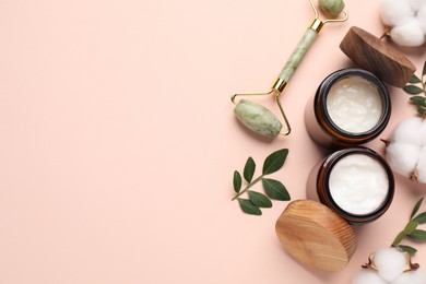 Photo of Different cosmetic products, cotton flowers and green leaves on beige background, flat lay. Space for text