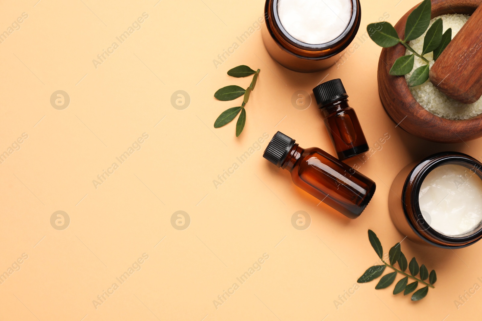 Photo of Different cosmetic products and leaves on pale orange background, flat lay. Space for text