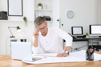 Photo of Architect making engineering drawing at wooden table in office