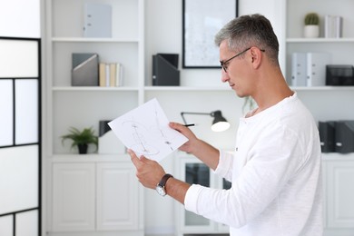 Photo of Architect holding paper sheet with engineering drawing in office