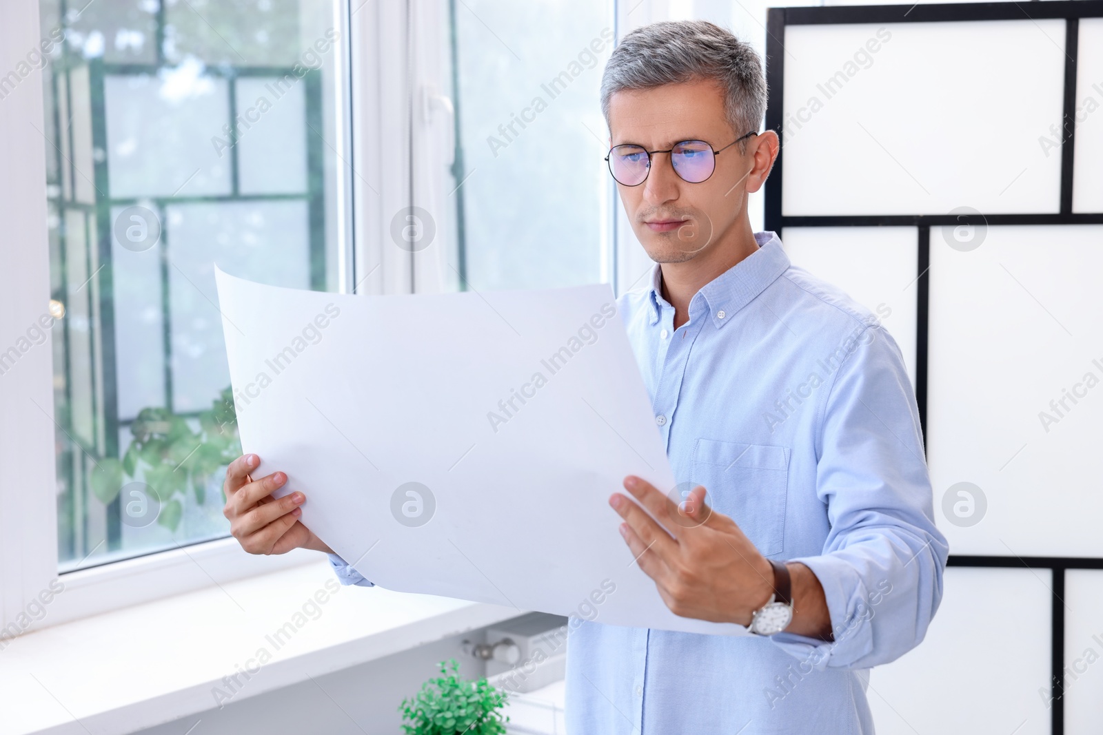 Photo of Architect holding paper sheet with engineering drawing in office