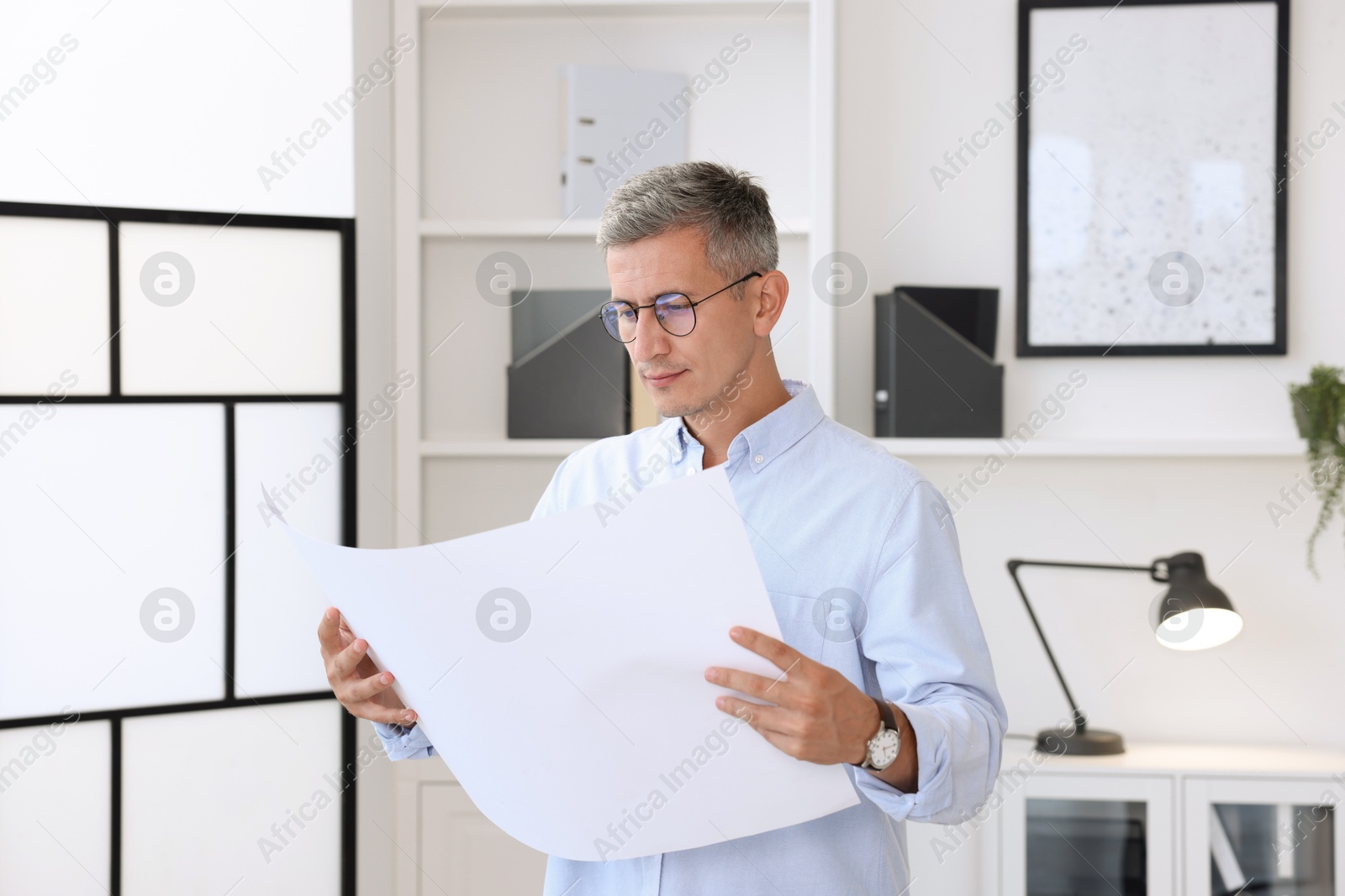 Photo of Architect holding paper sheet with engineering drawing in office