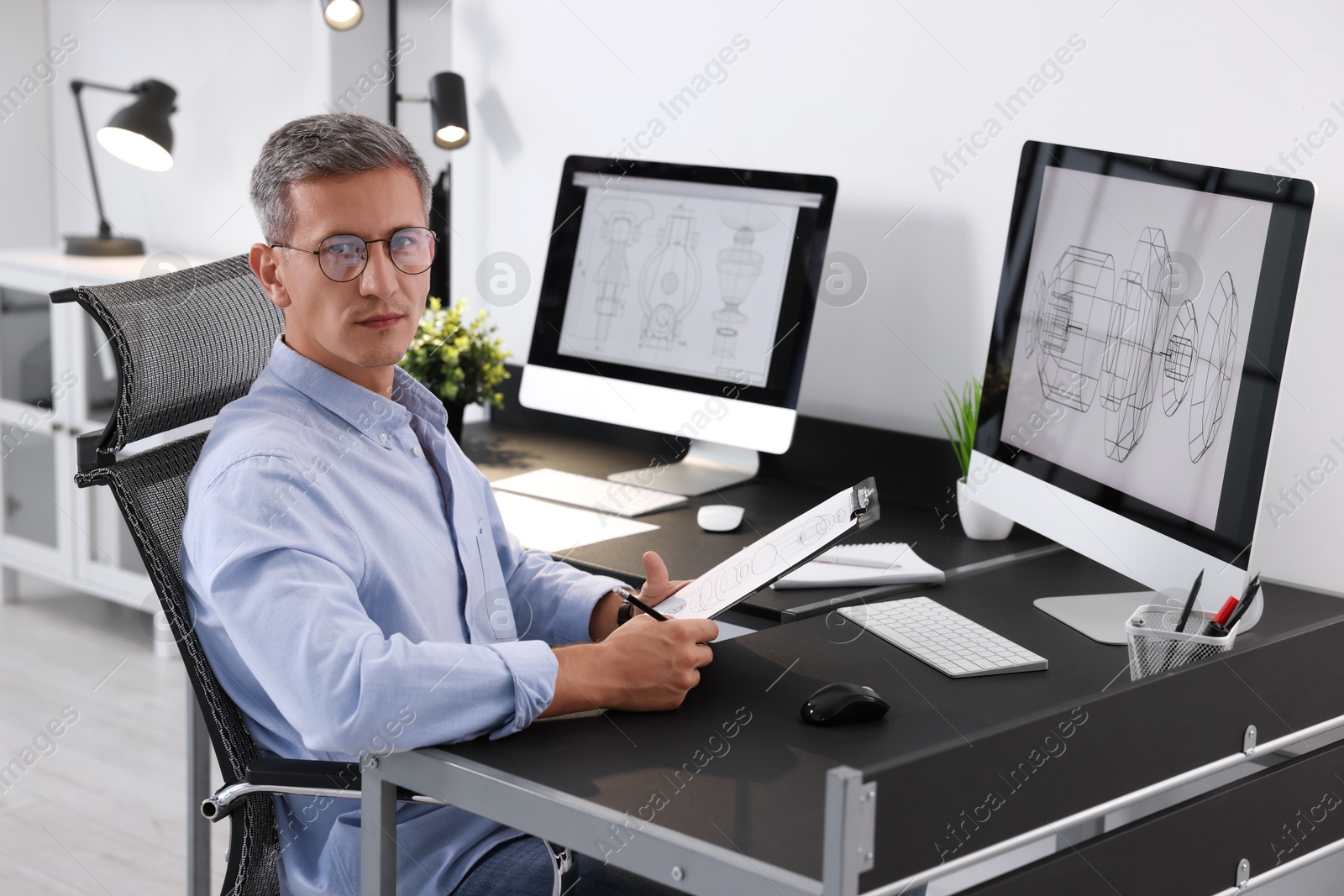 Photo of Architect checking engineering drawing at table in office