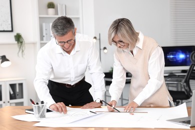 Architects making engineering drawing at wooden table in office