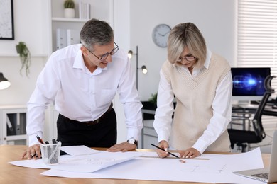 Architects making engineering drawing at wooden table in office