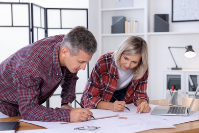 Photo of Architects making engineering drawing at wooden table in office