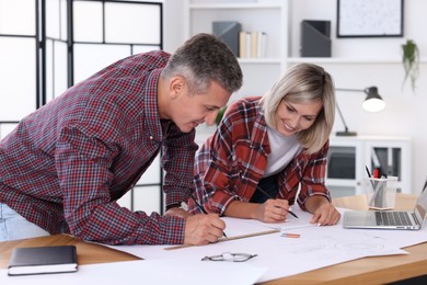 Architects making engineering drawing at wooden table in office