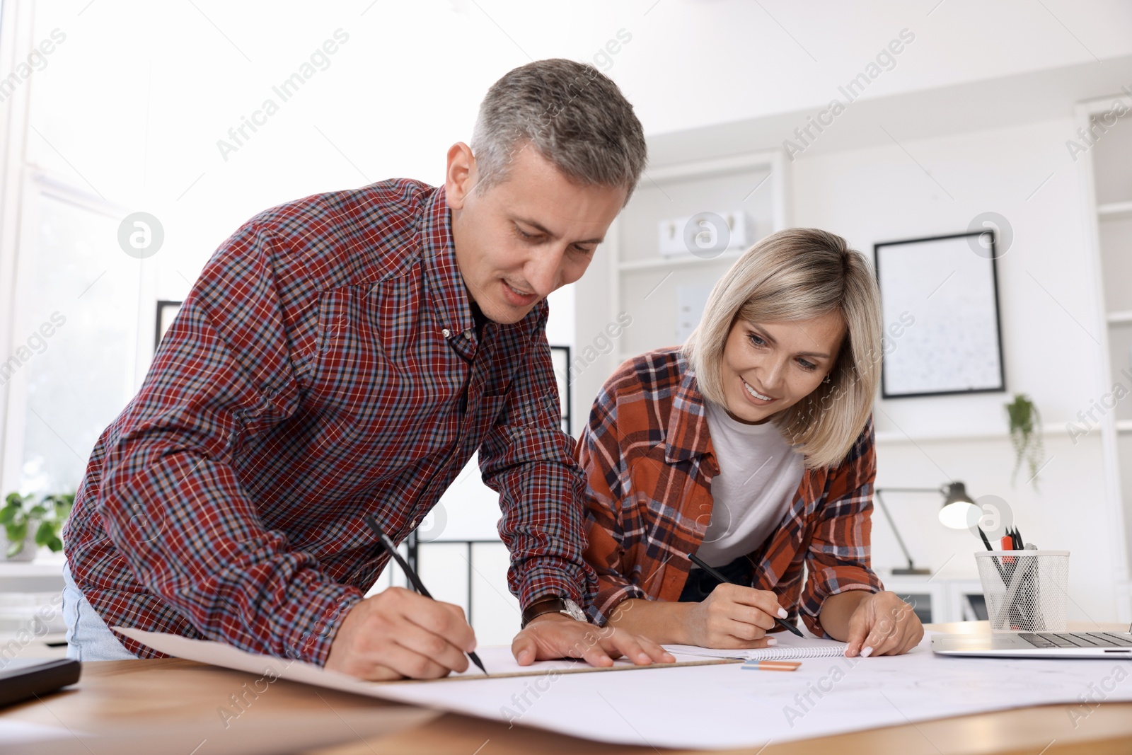 Photo of Architects making engineering drawing at wooden table in office, low angle view