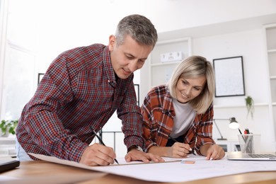 Photo of Architects making engineering drawing at wooden table in office, low angle view