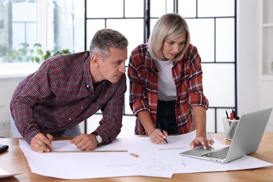 Photo of Architects making engineering drawing at wooden table in office