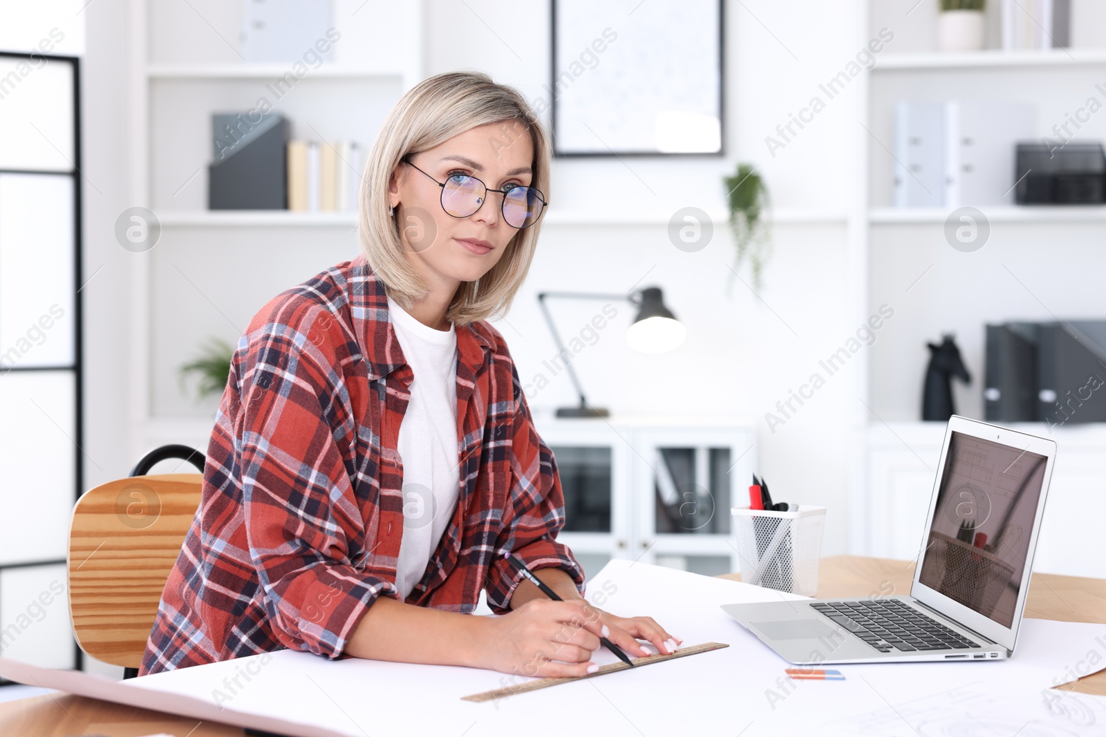 Photo of Architect making engineering drawing at table in office