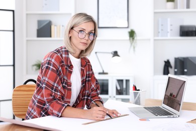 Architect making engineering drawing at table in office