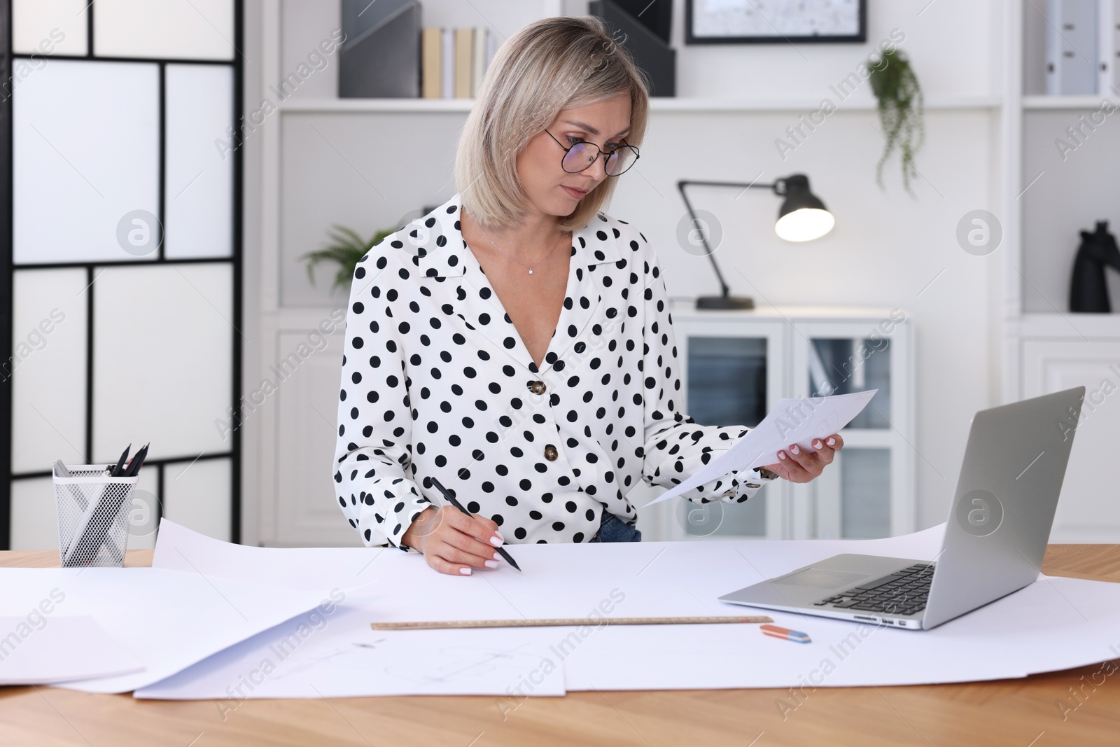 Photo of Architect making engineering drawing at wooden table in office