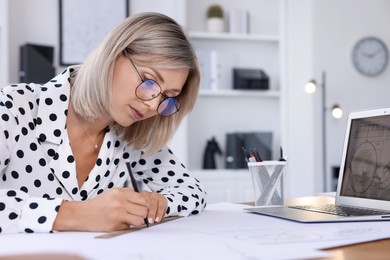 Architect making engineering drawing at table in office