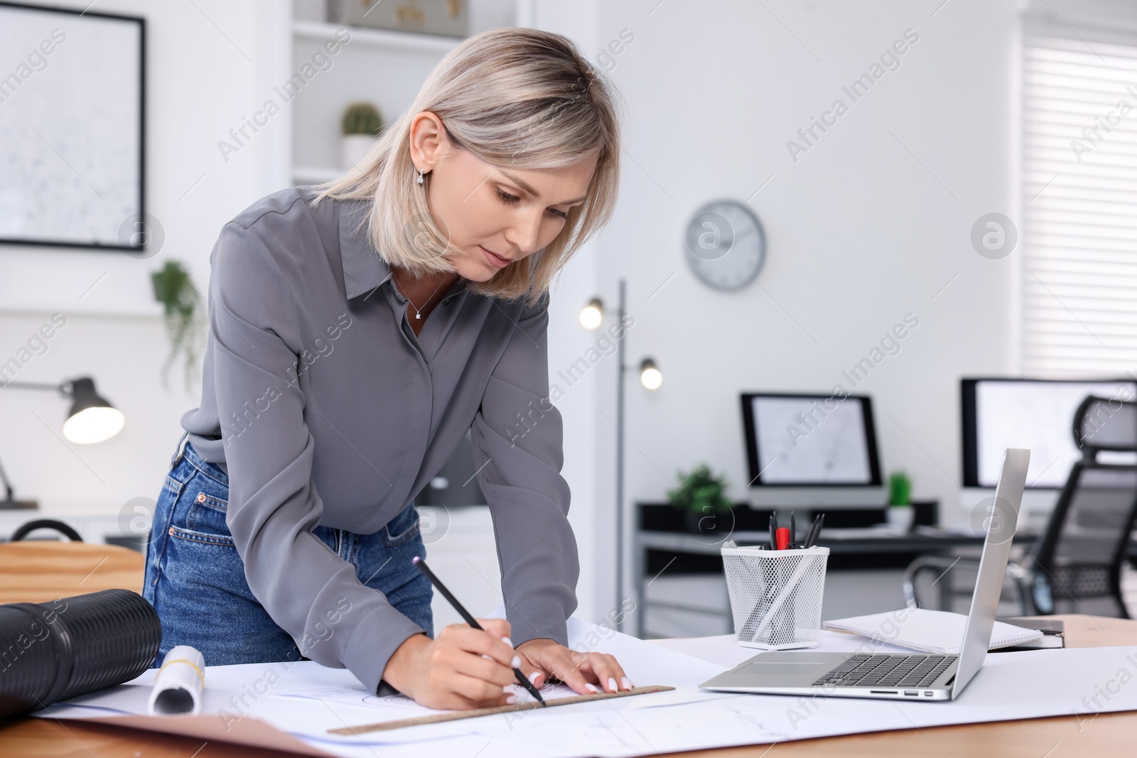 Photo of Architect making engineering drawing at wooden table in office