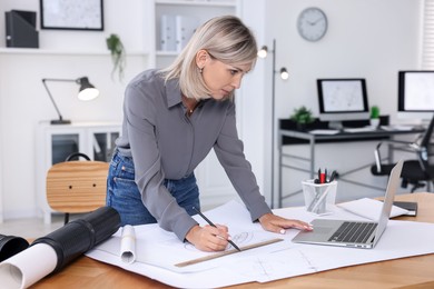 Photo of Architect making engineering drawing at wooden table in office