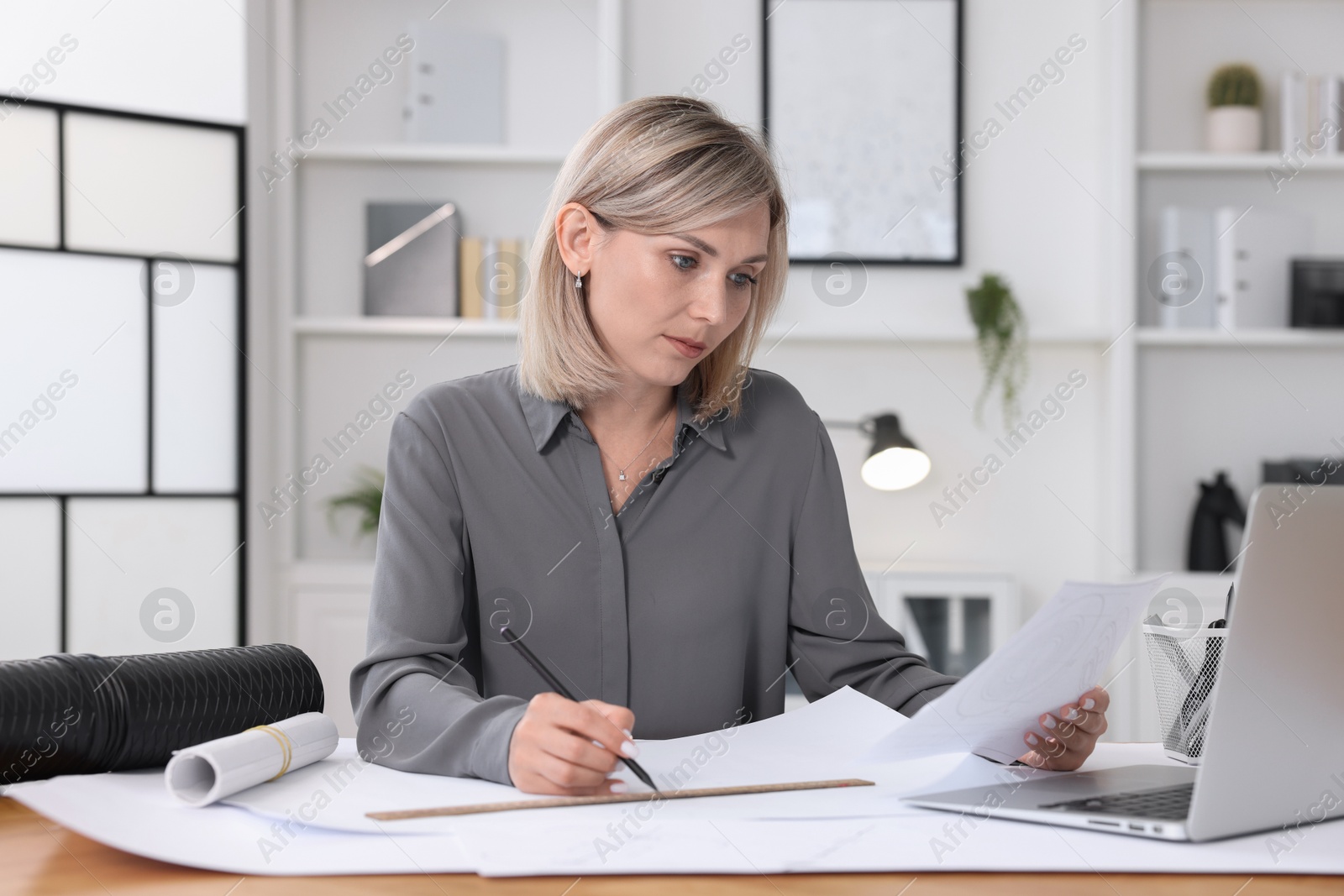 Photo of Architect making engineering drawing at wooden table in office