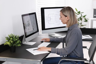 Architect making engineering drawing at table in office