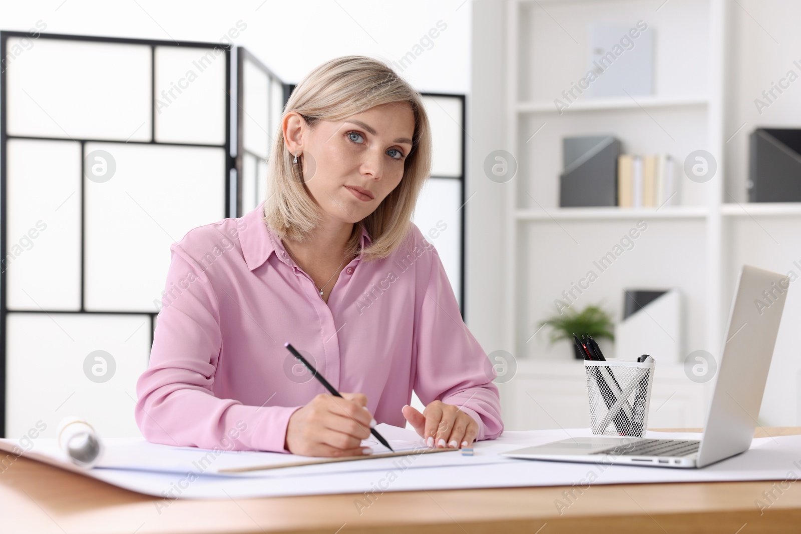 Photo of Architect making engineering drawing at table in office