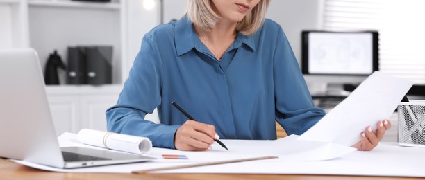 Photo of Architect making engineering drawing at table in office