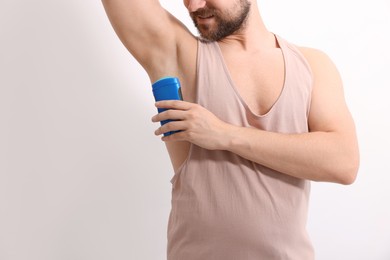 Smiling man applying solid deodorant on white background, closeup. Space for text