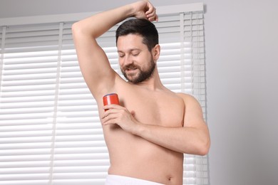 Smiling man applying solid deodorant at home