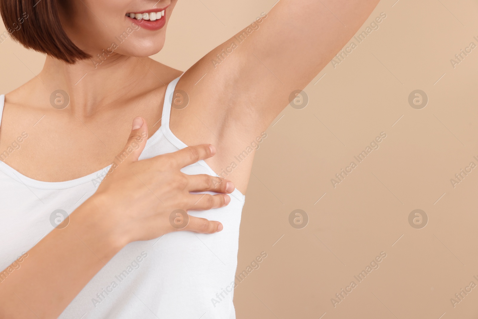 Photo of Smiling woman after using deodorant on beige background, closeup. Space for text