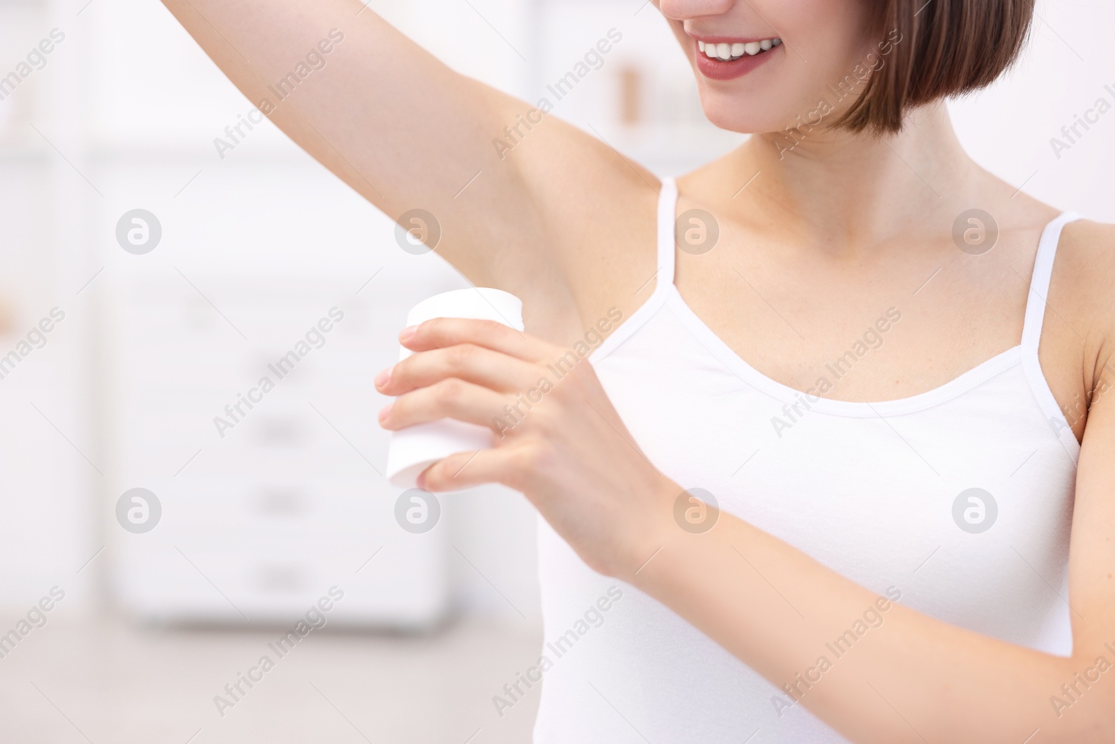 Photo of Smiling woman applying solid deodorant at home, closeup