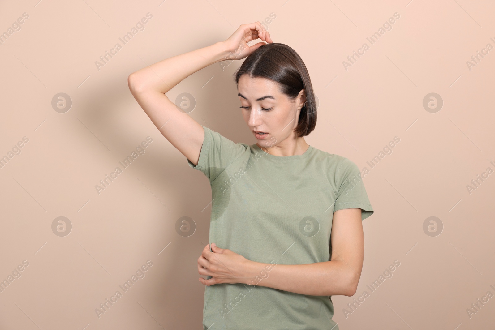 Photo of Emotional woman in t-shirt before using deodorant on beige background