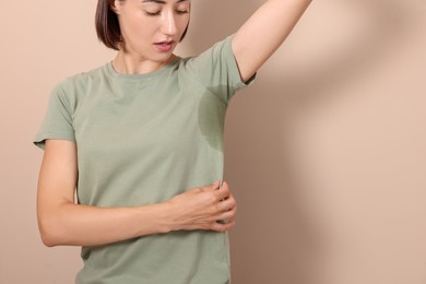 Woman before using deodorant on beige background, closeup