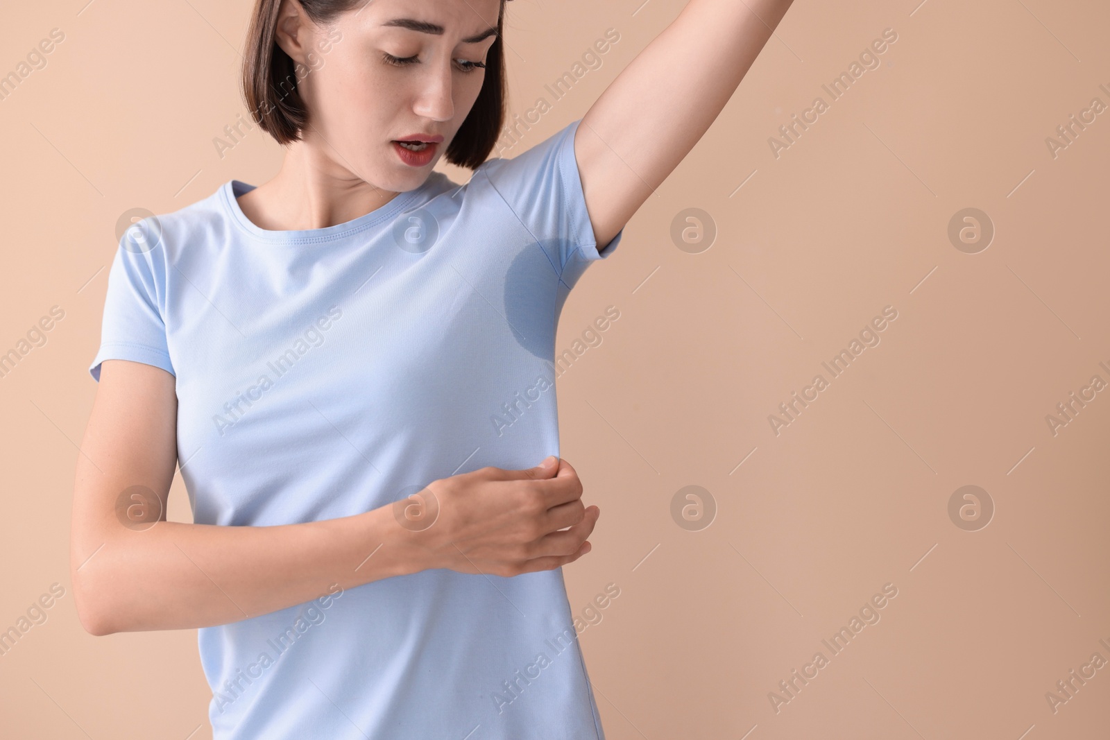 Photo of Emotional woman in t-shirt before using deodorant on beige background. Space for text