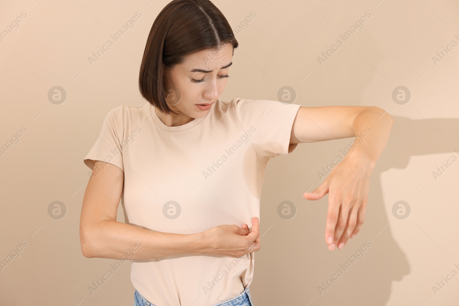 Photo of Emotional woman in t-shirt before using deodorant on beige background