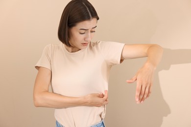 Emotional woman in t-shirt before using deodorant on beige background