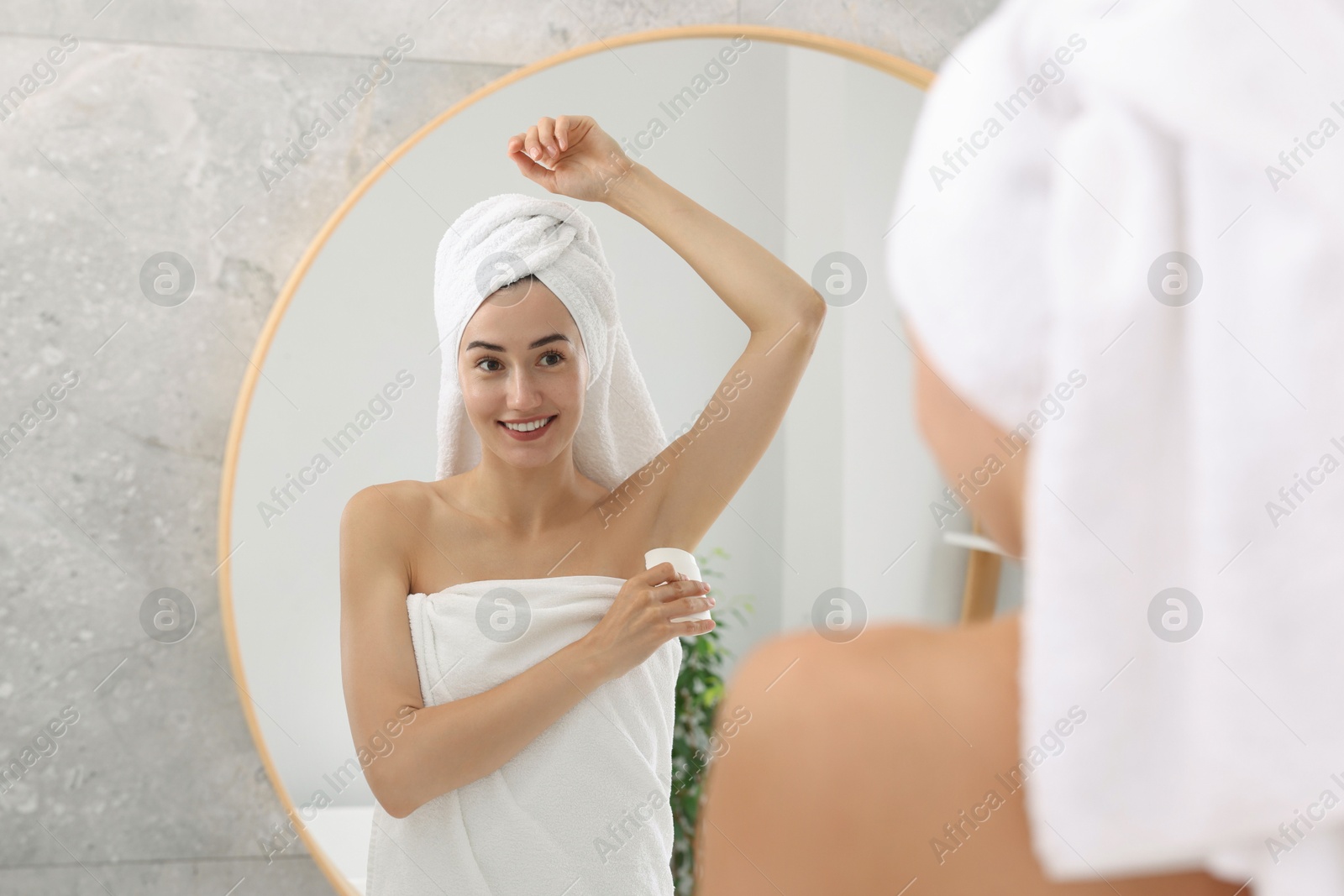 Photo of Smiling woman applying solid deodorant near mirror at home