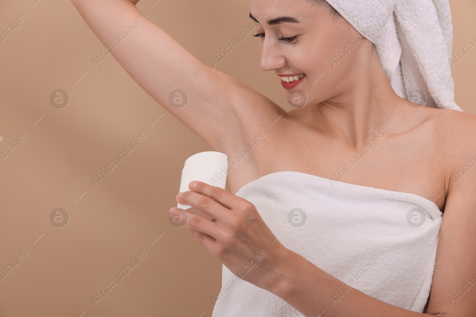 Photo of Smiling woman applying solid deodorant on beige background