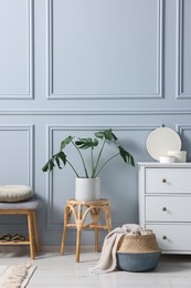 Photo of Stylish interior with stool and chest of drawers near light grey wall